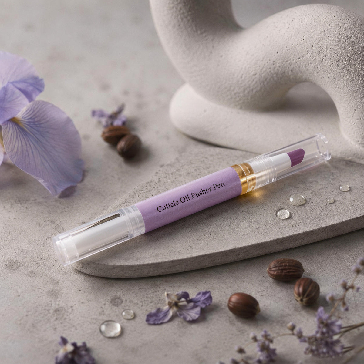 Cuticle oil pen in artistic flatlay composition on stone surface with water droplets and purple blooms